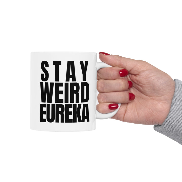 Stay Weird Eureka Mug being held