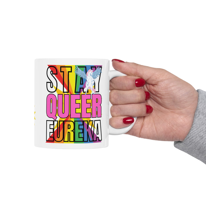 Stay Queer Eureka mug being held